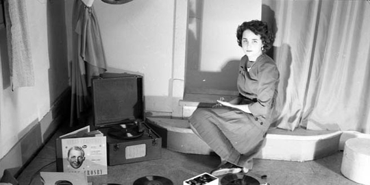 A young women posing with phonograph records and a record player.